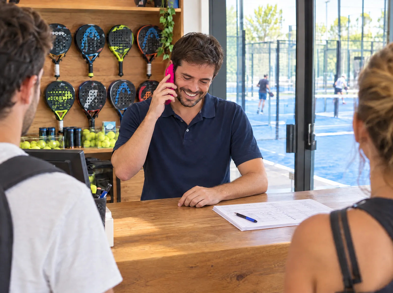 Con Sapiens: el mismo recepcionista habla por teléfono riendo, con el mostrador ordenado.